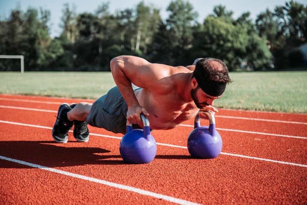 man doing push ups using kettlebells to work his core. A core workout for your abs can be obtained without doing crunches. 