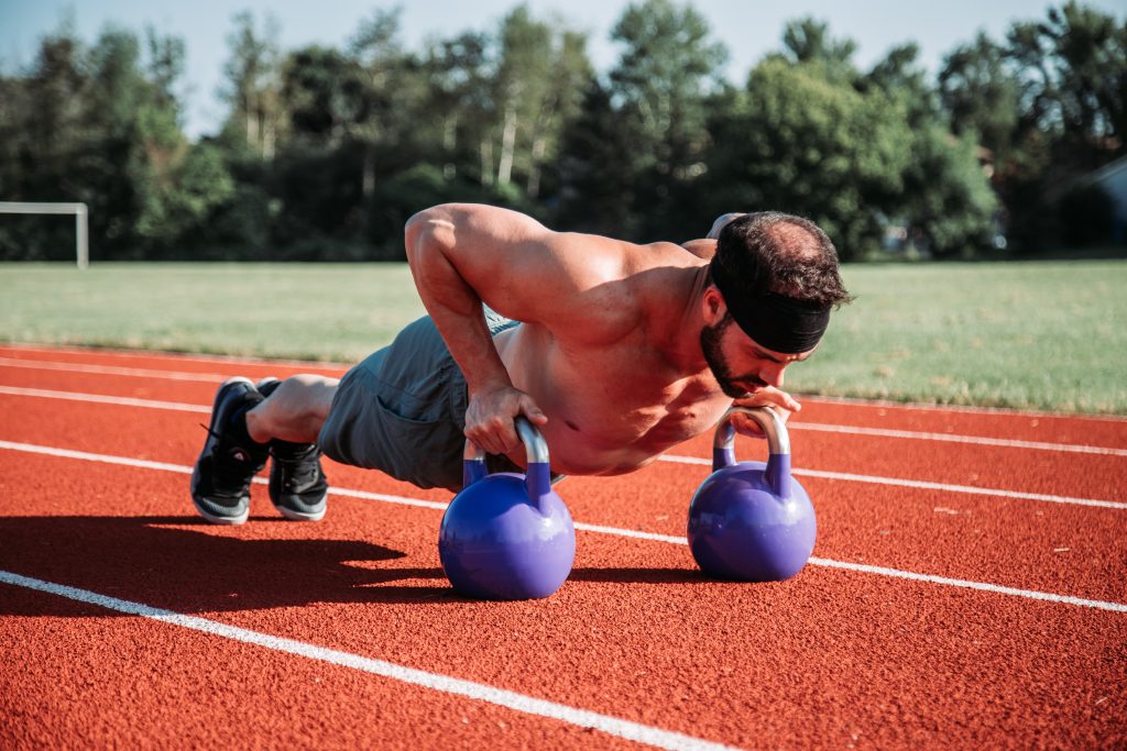 man doing push ups using kettlebells to work his core. A core workout for your abs can be obtained without doing crunches.