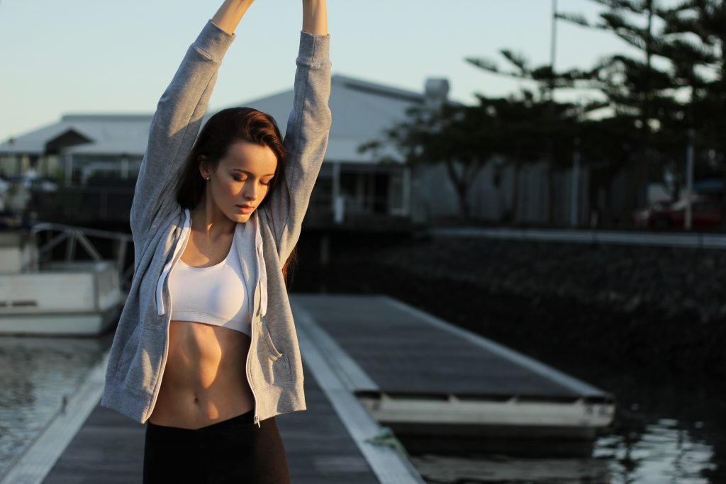 A fit woman stretching her arms showing her gut health diet.