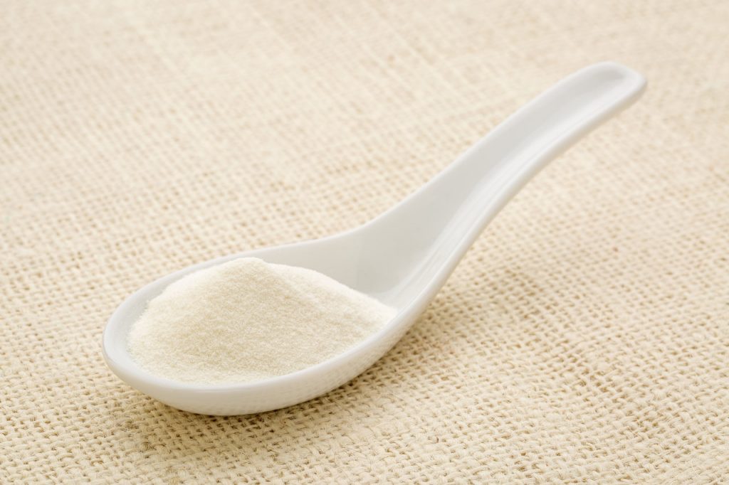 A spoonful of collagen powder used for collagen supplements.