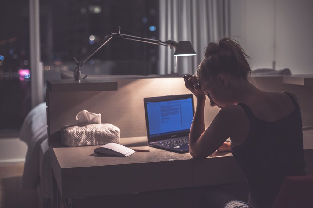 Exhausted woman sitting in her room in front of her laptop.