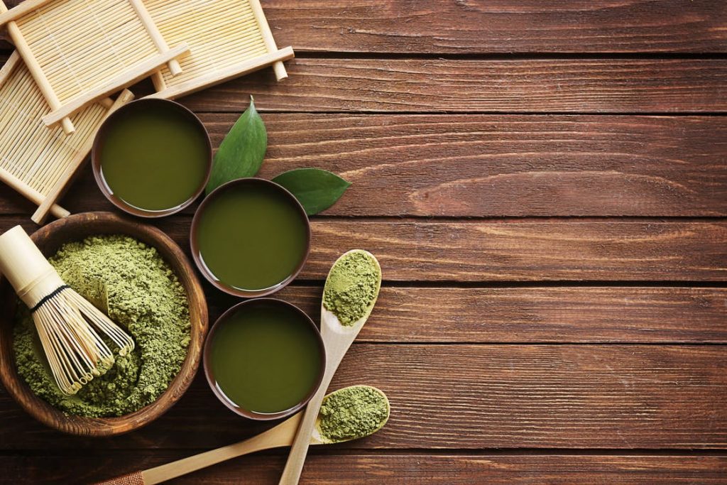 Green tea in cups on a wooden table.