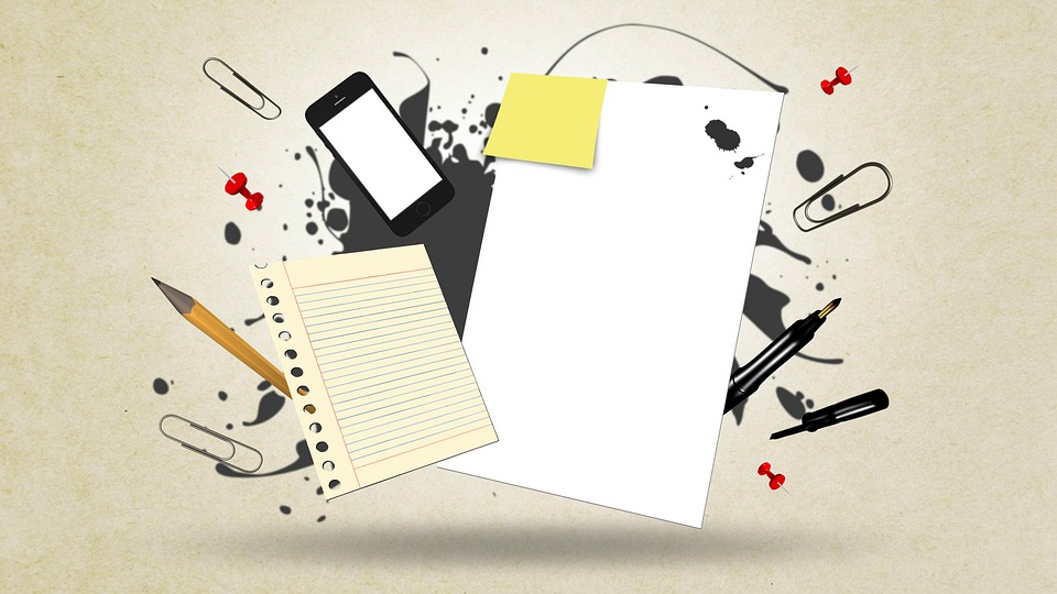 A phone, paper, sticky notes and pens to keep track of goals as part of a weight loss strategy