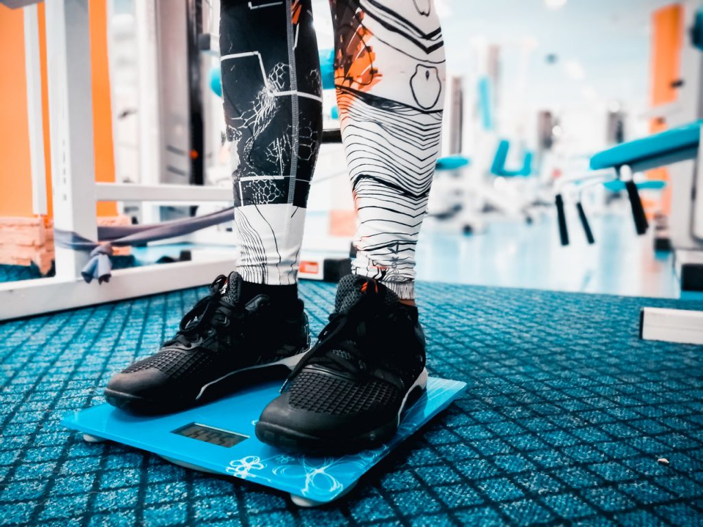 Person weighing by standing on a scale. When is the best time to weigh?