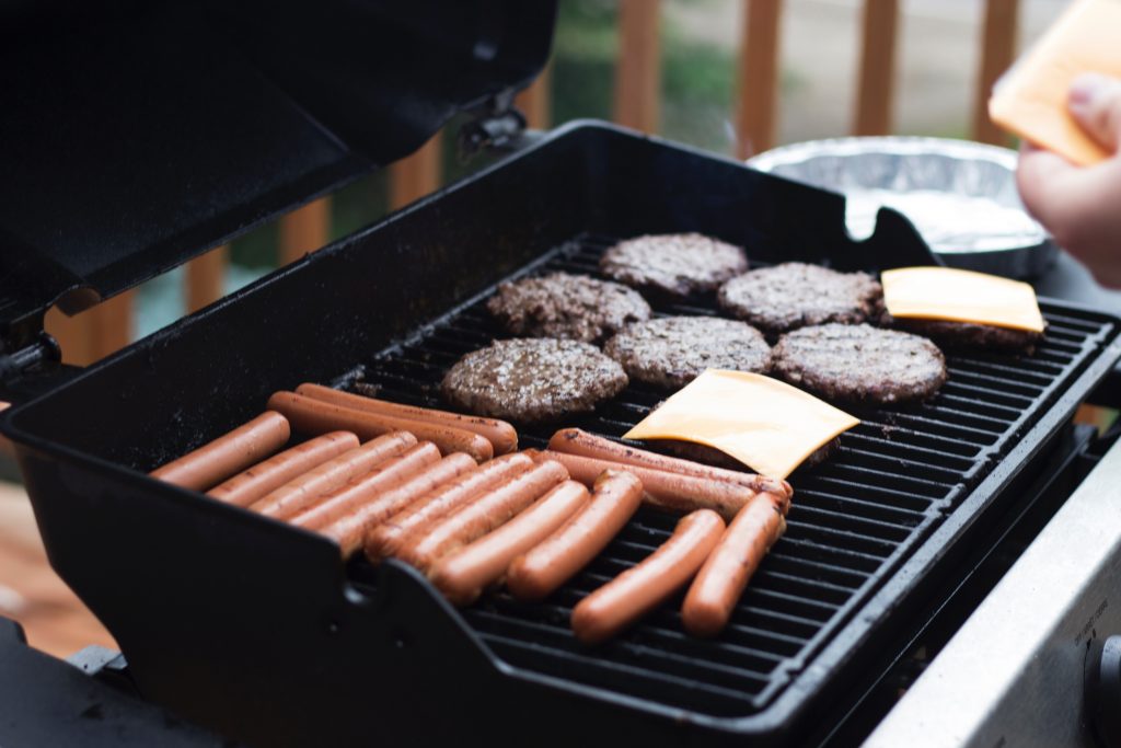 Burgers and hot dogs cooking on a grill. Would you like some healthy ground beef recipes?