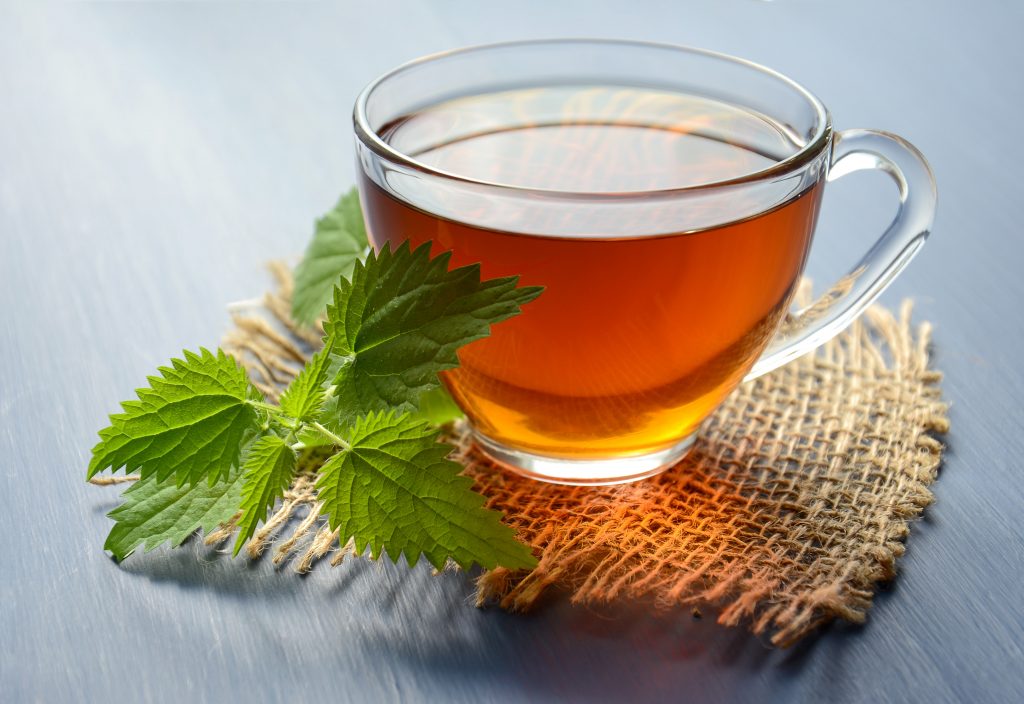 a close up photo of peppermint tea in a cup next to peppermint leaves