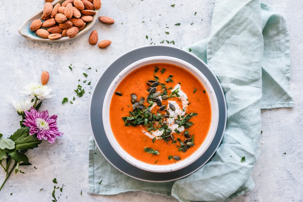 A bowl of pumpkin soup with whole almonds on the side, a winter soup recipe.