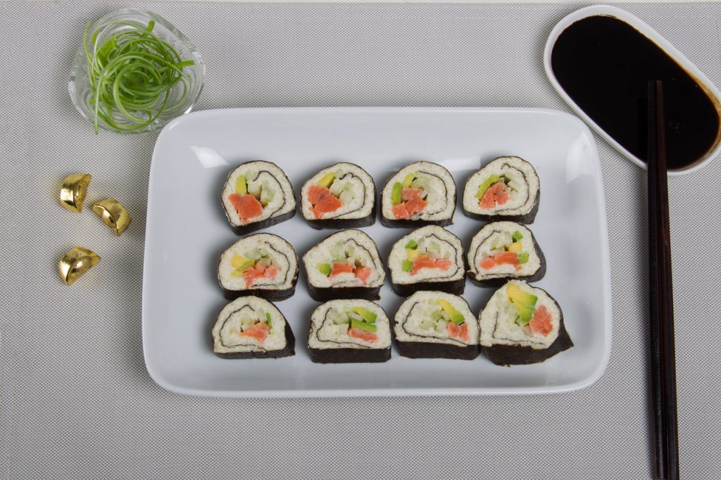 Spicy tuna sushi roll using cauliflower rice served on a platter with soy dipping sauce.