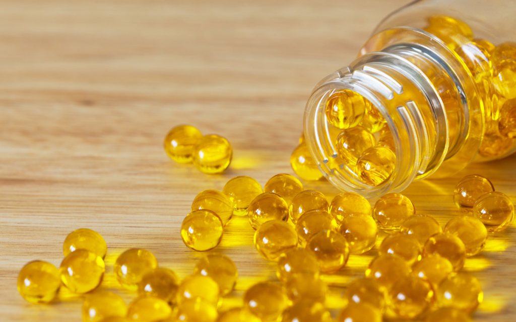 Which vitamins are fat soluble? Softgel capsules with fat-soluble vitamins scattered on a wooden surface is an example.