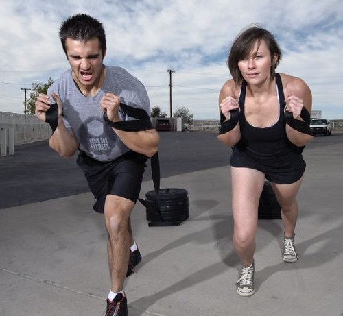 A man and woman doing sled training