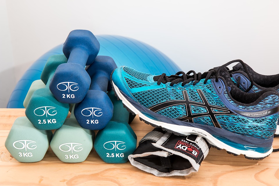Stack of dumbbell and a pair of sneaker. Should you do cardio before or after weights?