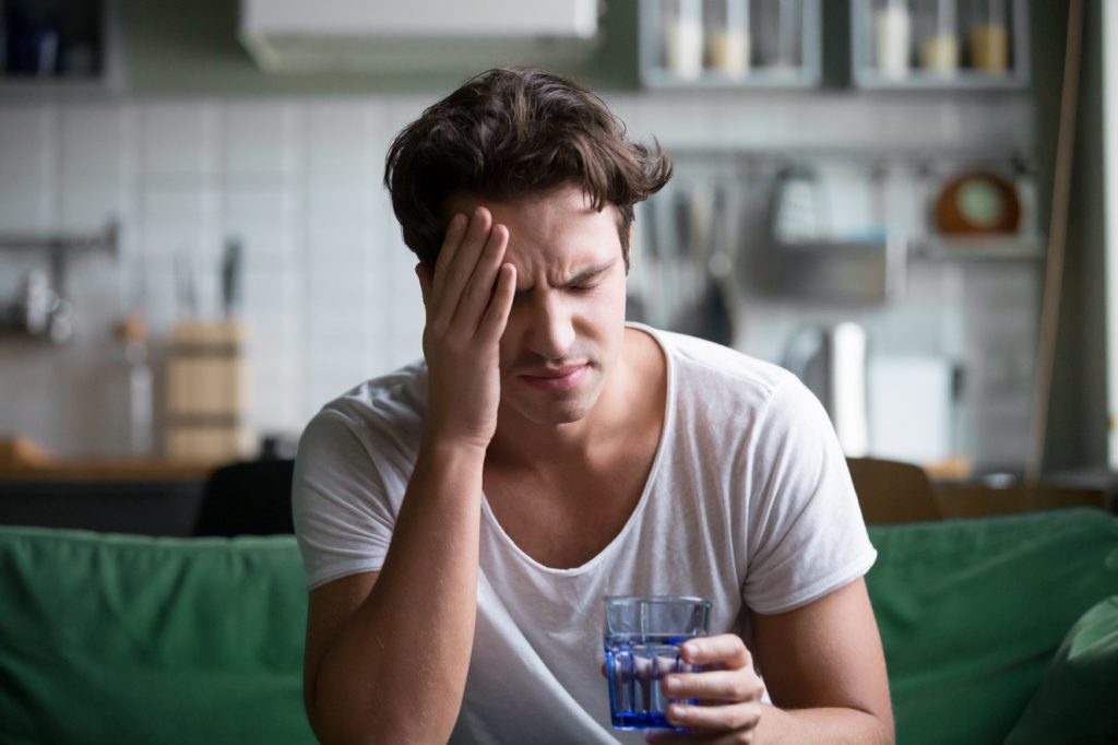 Man having a headache after a night of drinking, which shows how important it is to drink responsibly and to know which foods to eat before drinking to help with the hangover.