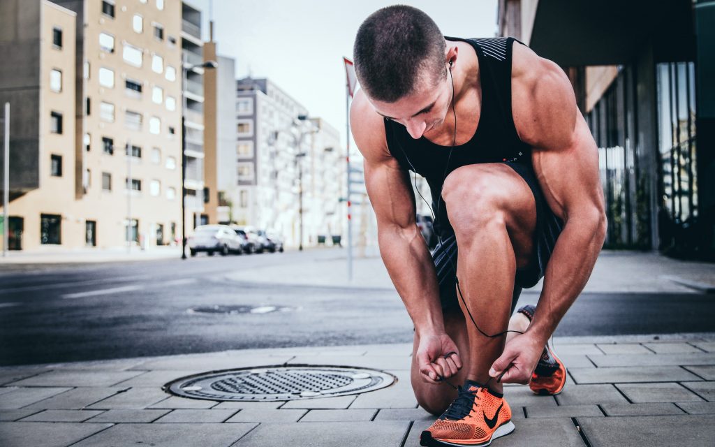 Man tying shoes in the urban setting before a run to prepare for his winter workout and diet.