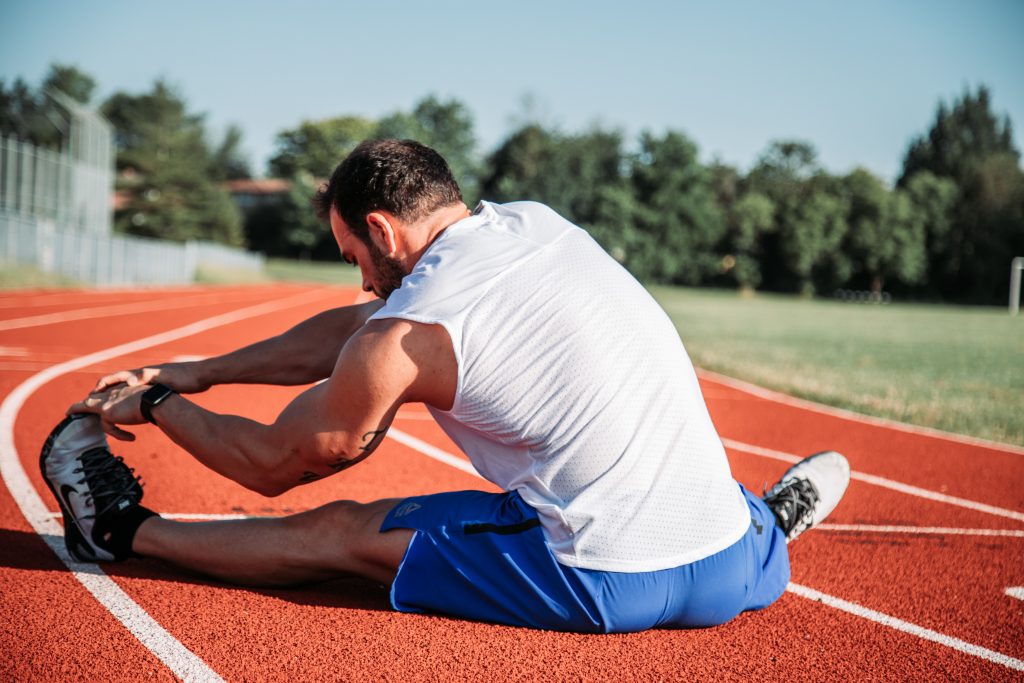 Man doing some stretches on a running track.