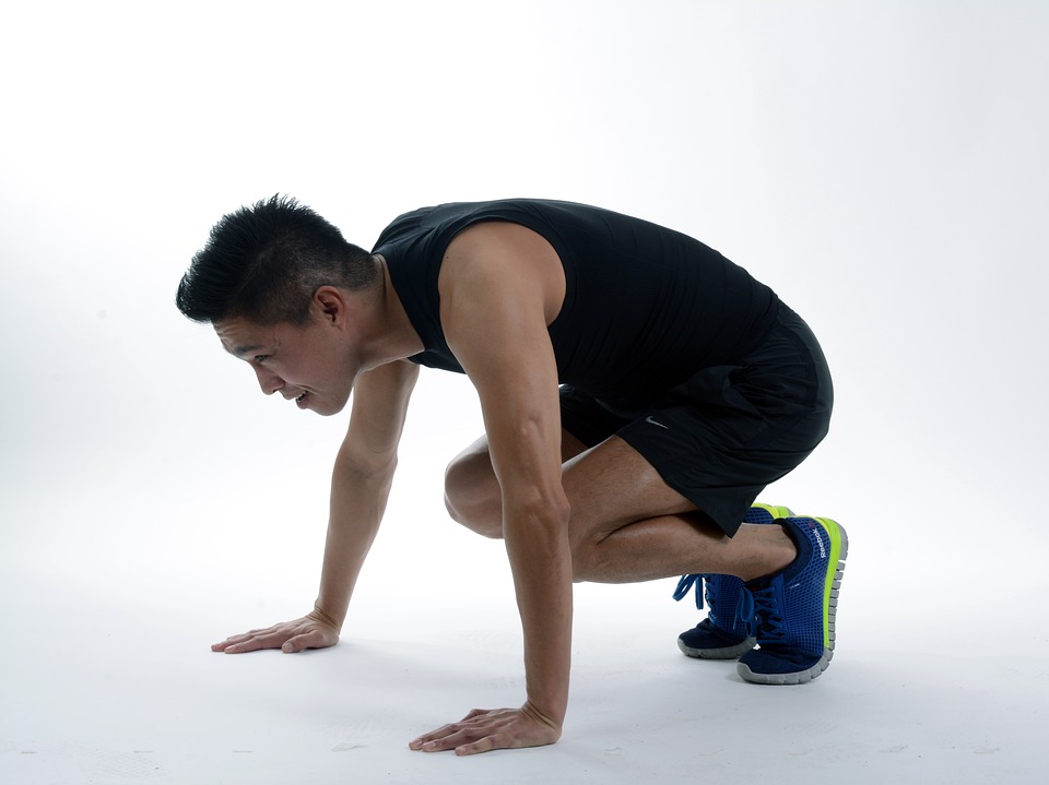 A man doing one of the burpees position ready to jump.