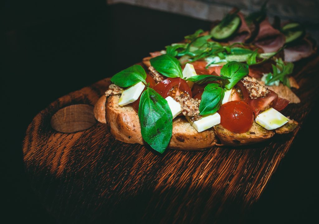 close up of a sandwich with fresh basil, tomatoes, and mozzarella cheese