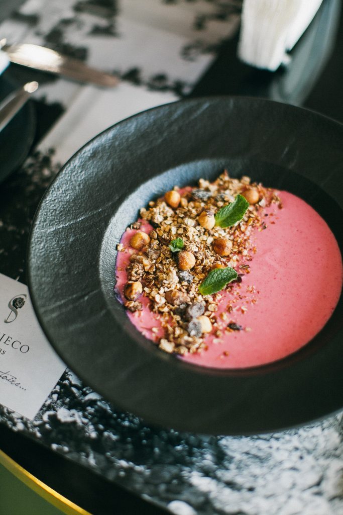 Close up shot of red yogurt in a black bowl as an example of unhealthy foods
