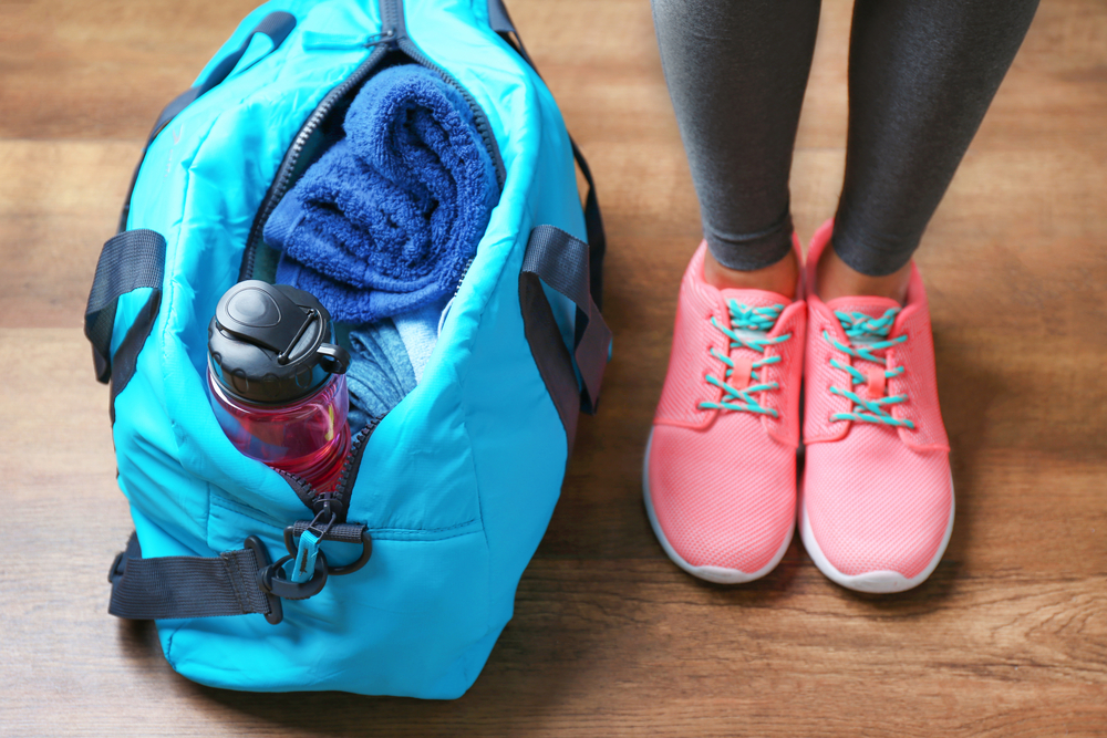 Woman standing next to workout bag, to bring to the gym for her winter workout.