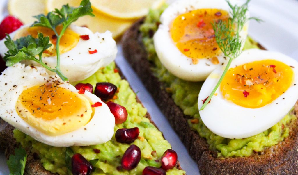 Eggs on top of avocado on slices of bread. 