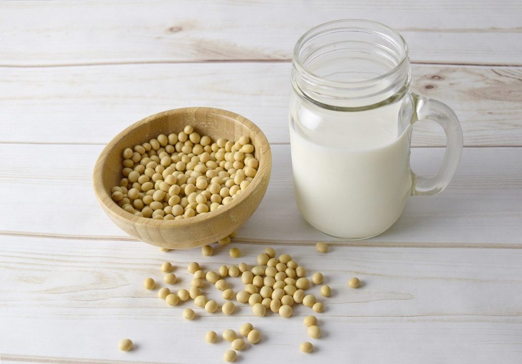 Soy milk in a mason jar next to a bowl of soy beans.