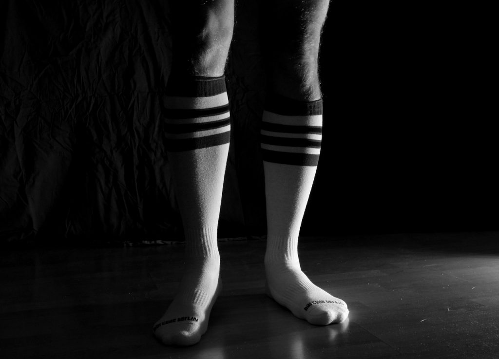 Man wearing sport socks in the dark. Should you wash your socks after every workout?