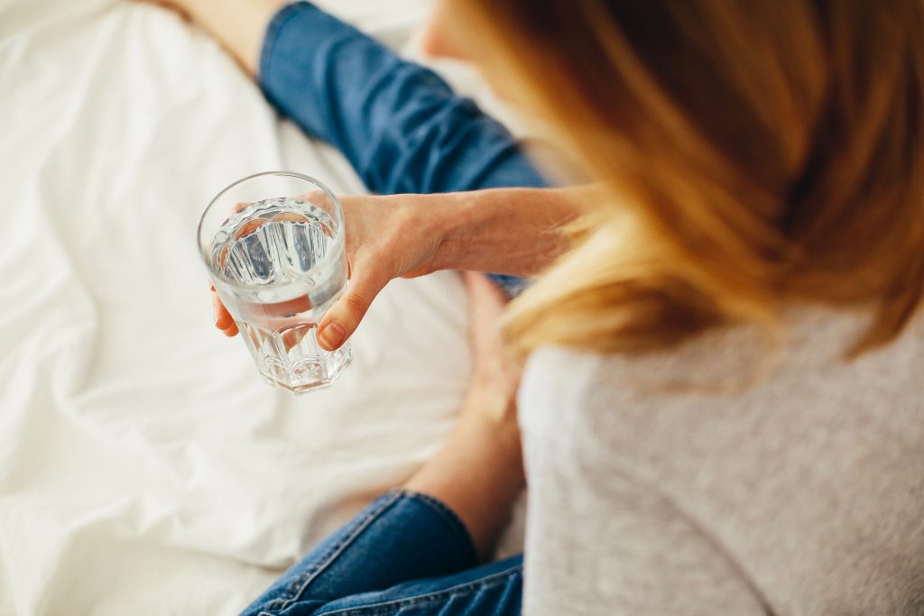 Woman holding a glass of water. How to stop binge eating? Drinking more water helps you feel full even with just a small amount of food.