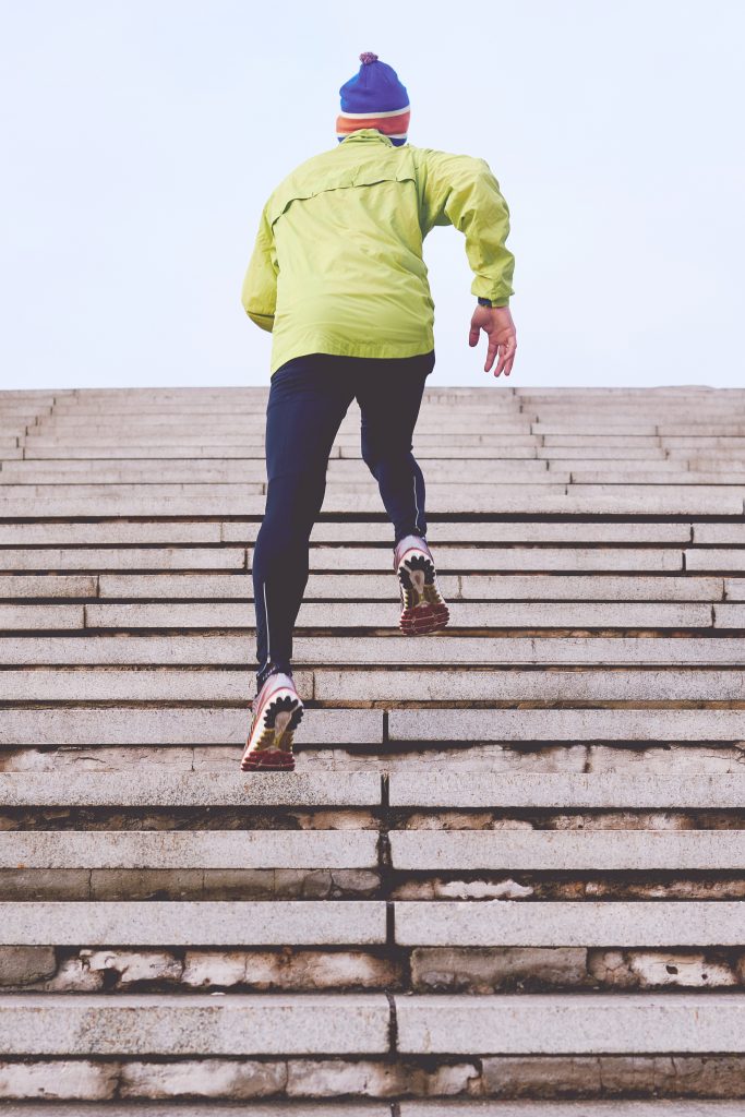 Man running up steps using appropriate running gear for men.