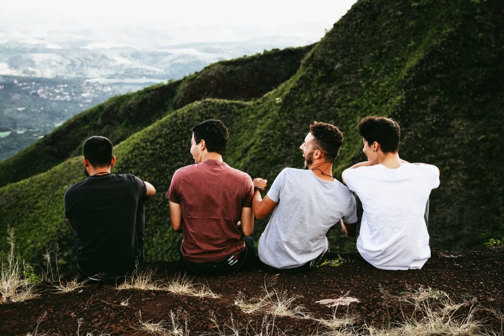 4 men laughing together while having a conversation on a hill. Is this part of life's purpose?