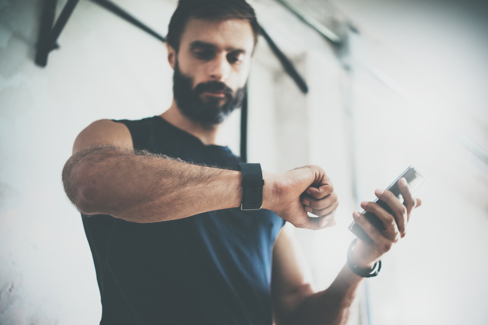 Man reading fitness watch on his wrist. Part of the food and health trends means having a good data tracker and having healthy meals.
