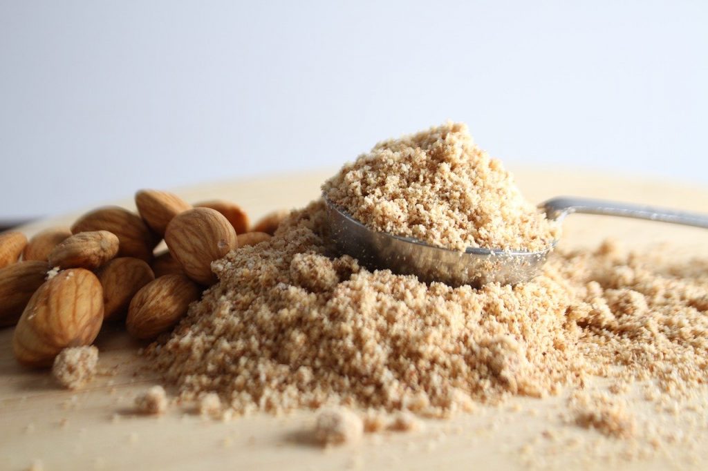 Close up image of almond flour and some almonds.