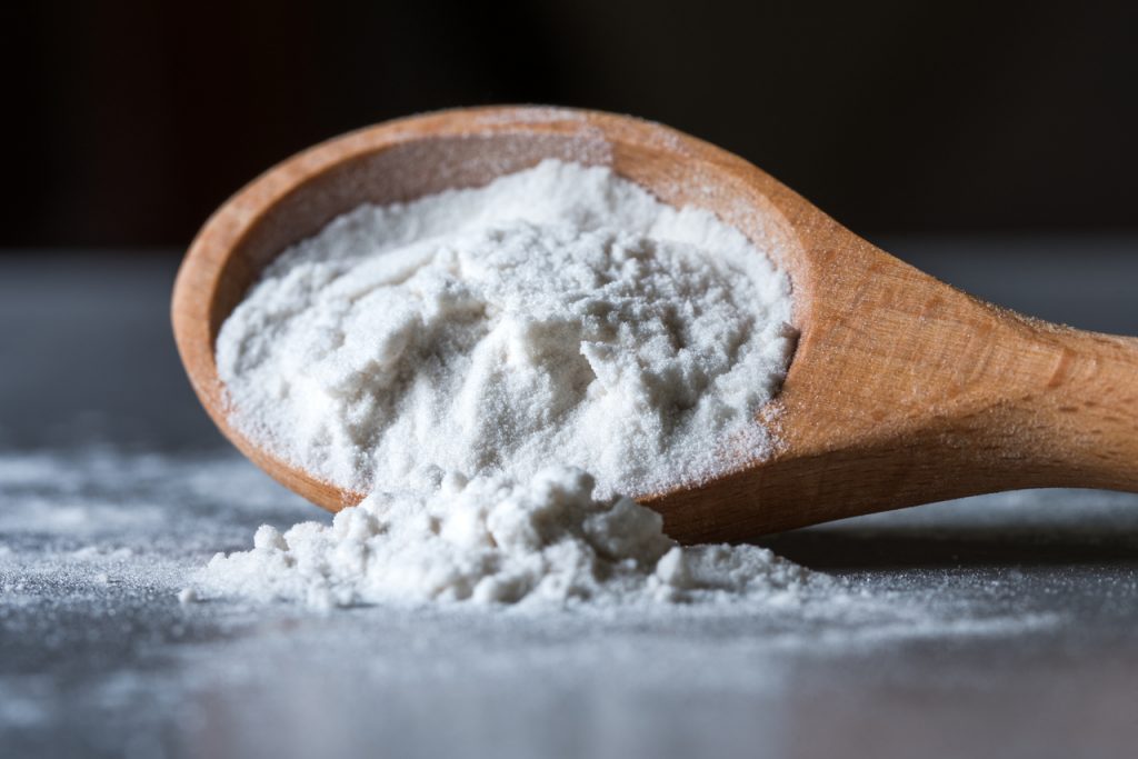 Arrowroot powder spilled from wooden spoon.