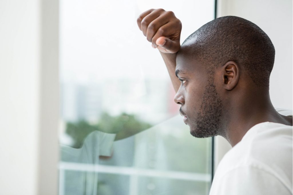 Man looking out the window showing signs of millennial depression.