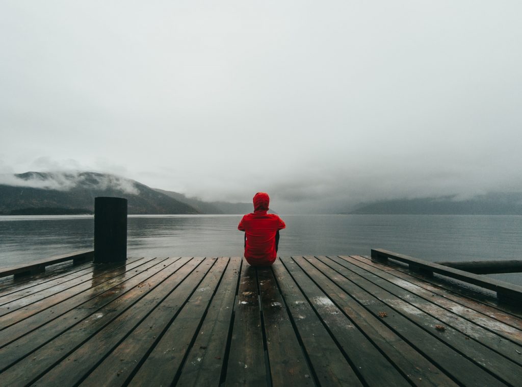 Lonely man sitting by the lake.