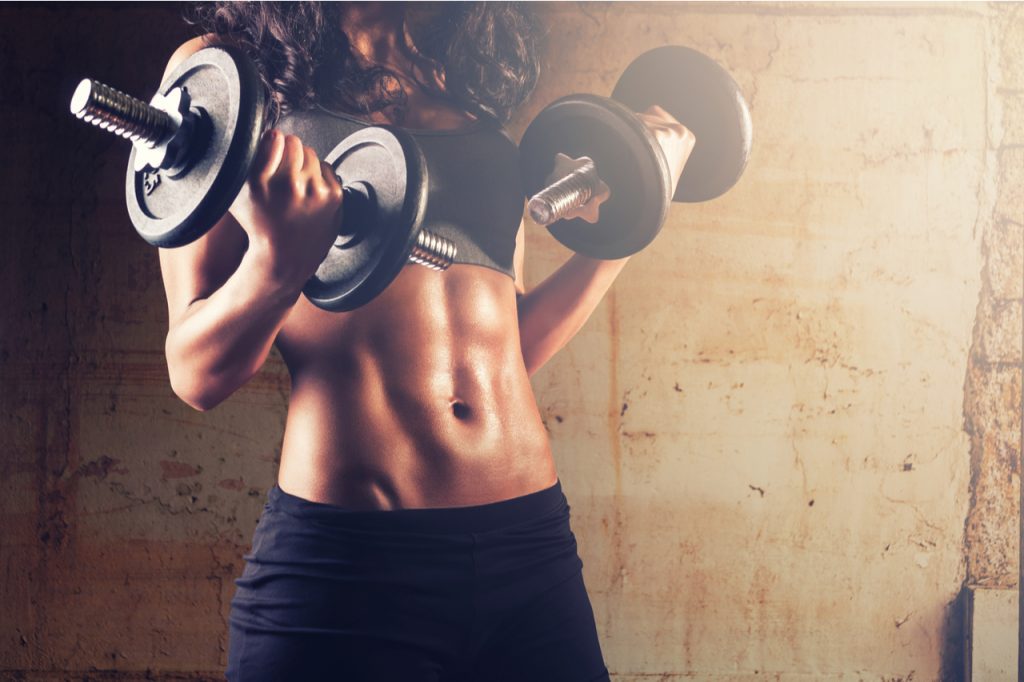 A woman doing an exercise using dumbbell as part of weight training for fat loss.