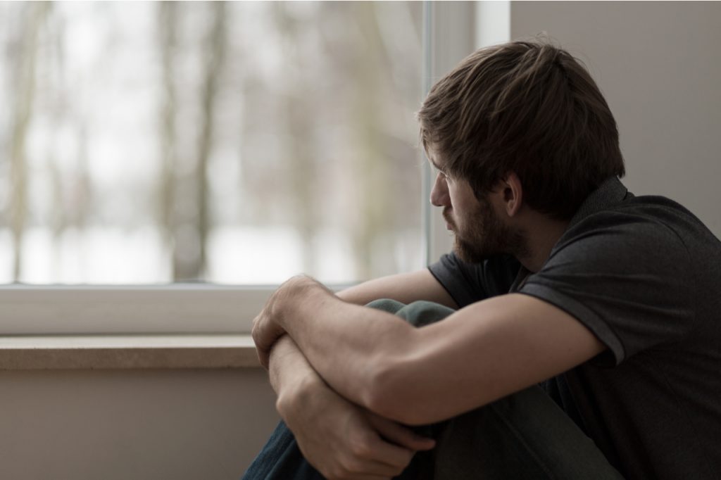 Depressed man sitting by the window.