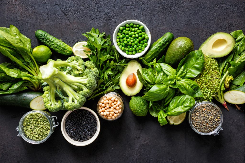 Different plants like vegetables, seeds, and beans on a table shown as protein sources.