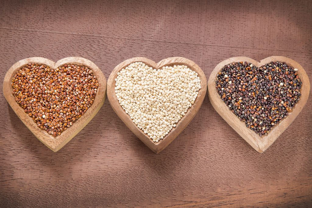 Complete-protein quinoa in three colors in heart-shaped wooden bowls.