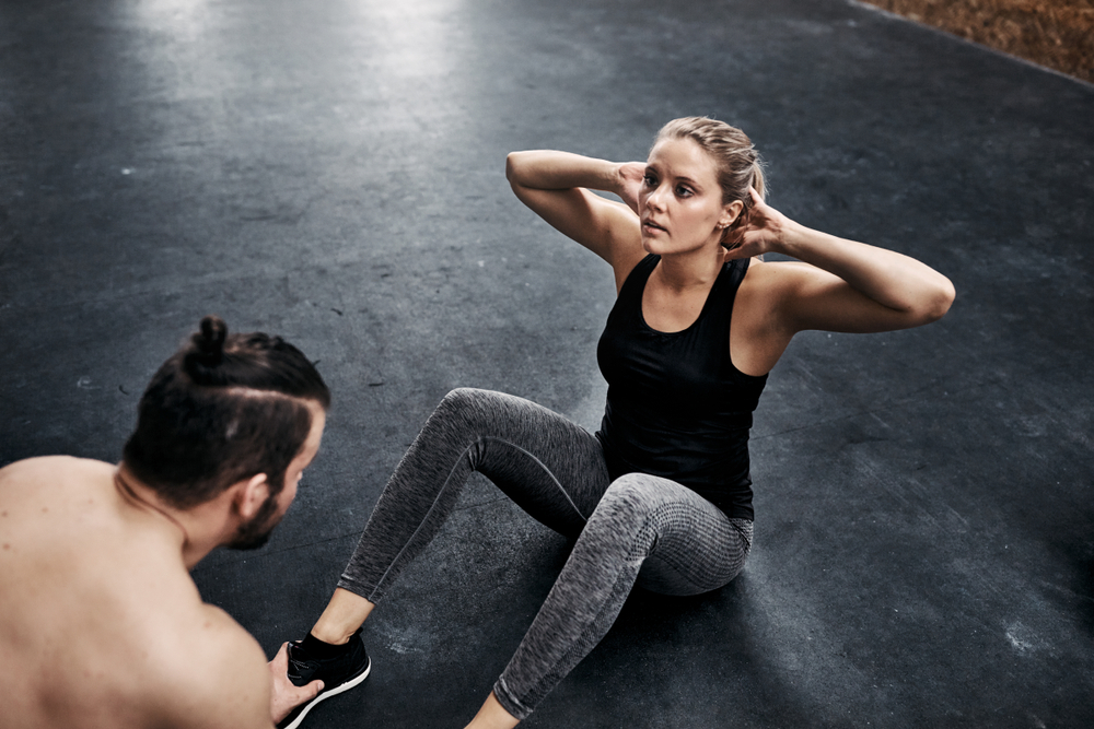 Woman doing crunches with partner. 