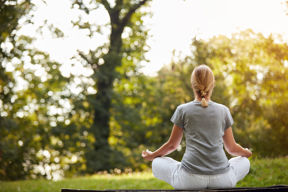 A woman meditating with nature as background.