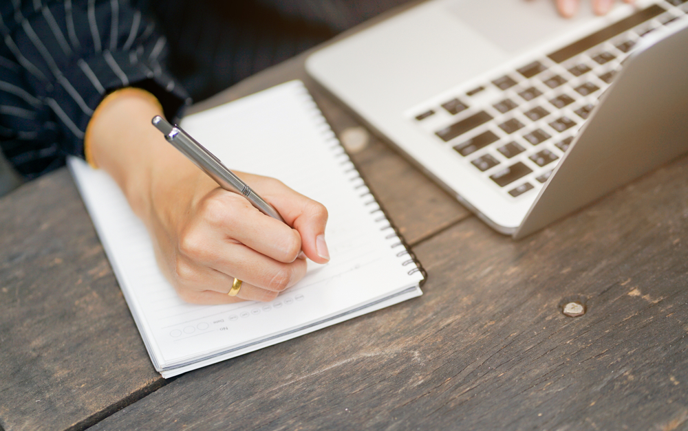 close up businesswoman hand writing contents on notebook