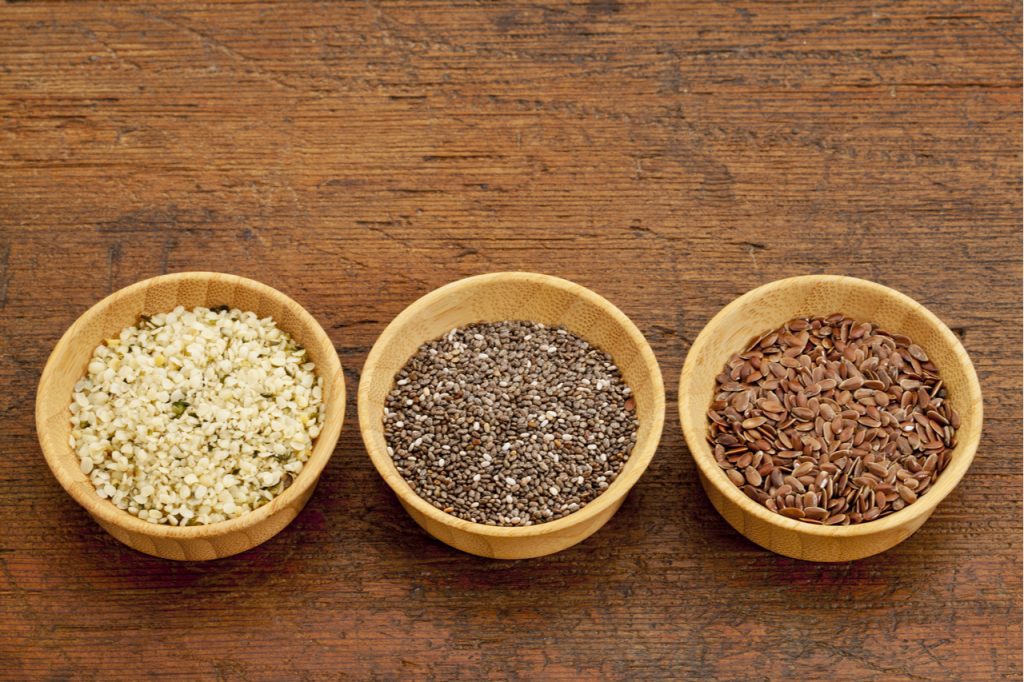 Chia seeds, flaxseeds, and hemp seeds in wodden bowls.