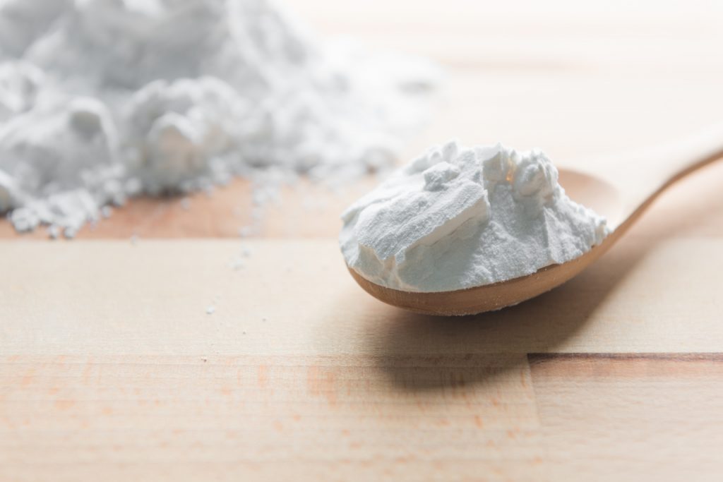 Tapioca flour in wooden spoon on a wooden table.
