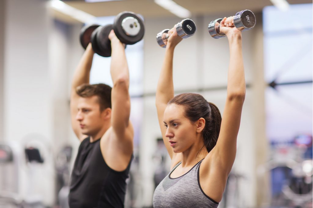 Man and woman lifting dumbbells at the gym.