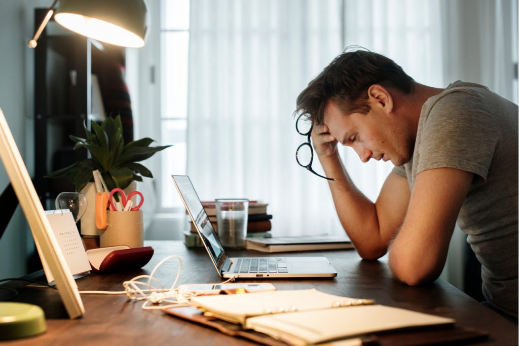 An image of a man looking stressed out due to work which would not happen if he knows how successful people think.