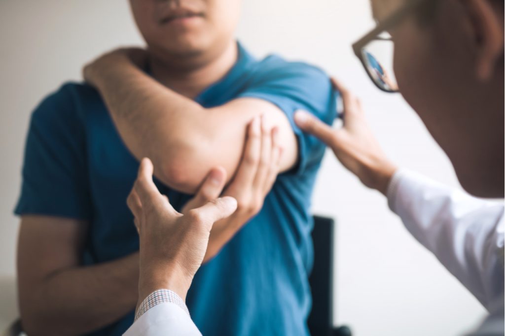 A man having his elbow checked by a physician.