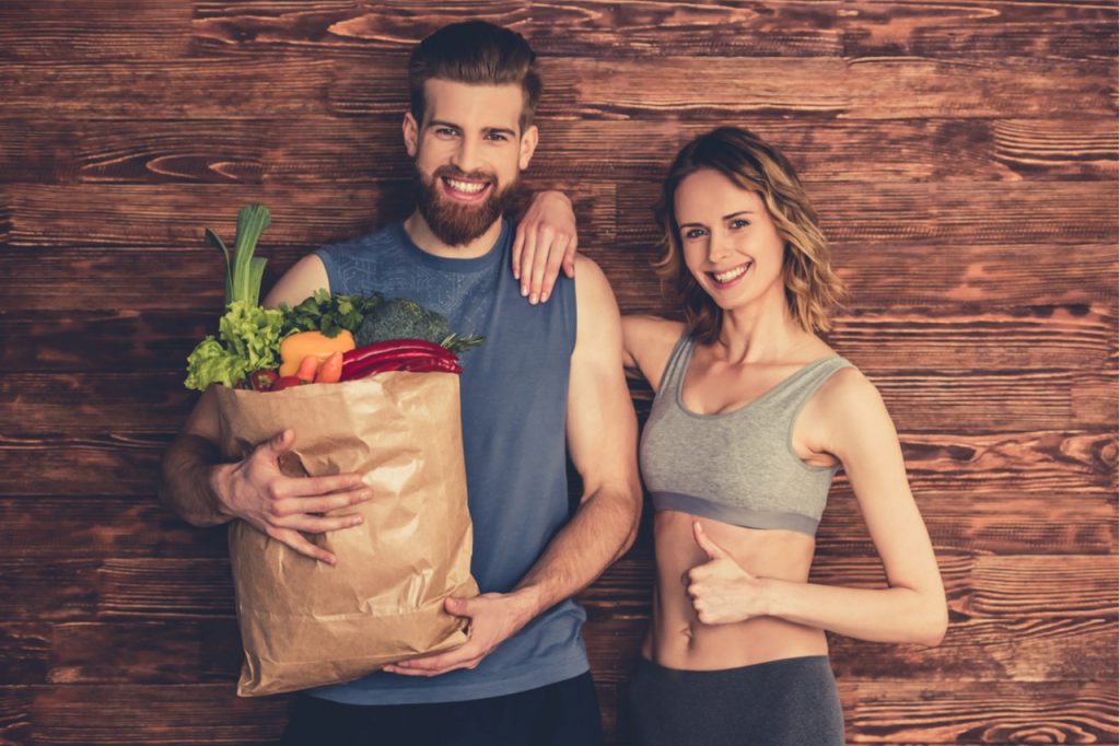 A man and woman staying healthy by selecting healthy products through grocery shopping.