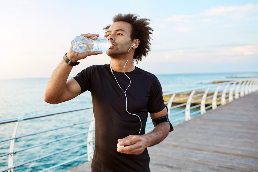 Man drinking water after jogging. Hydration is just one of the many water benefits.