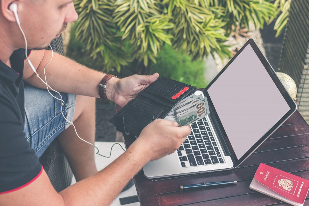 A man sitting in front of his laptop, while counting how much cash he has in his wallet. There are things that can be done now to invest in health that will save you money later in life.