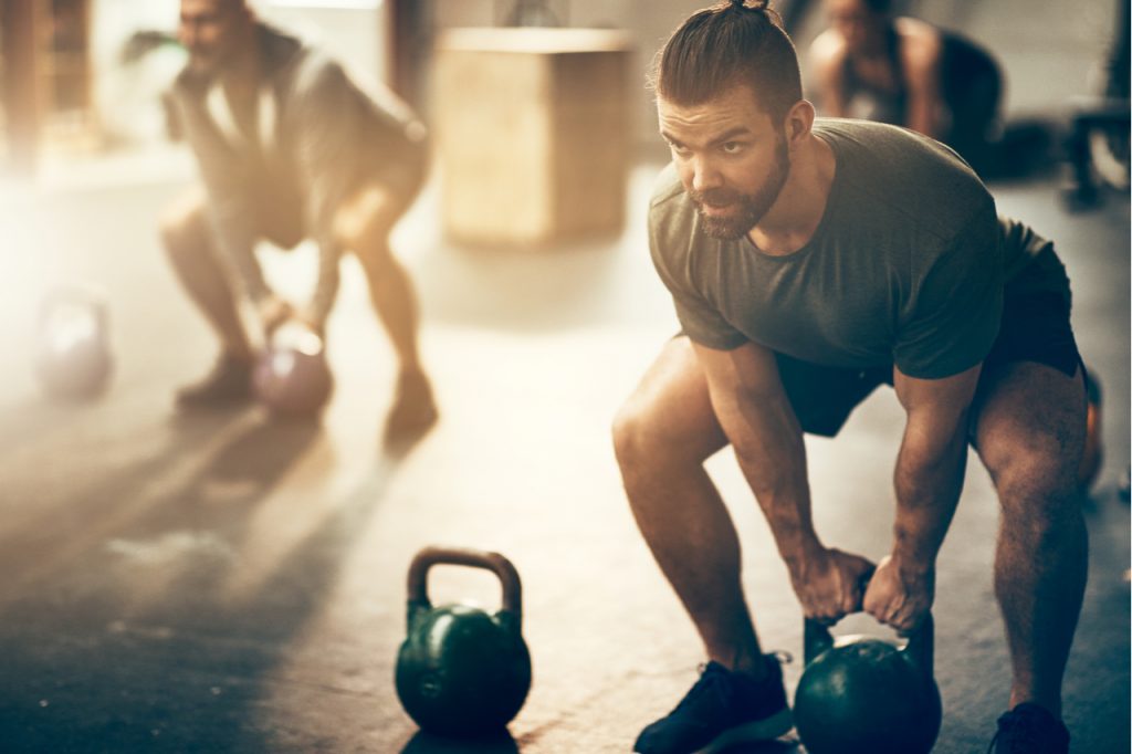 A man doing some kettlebell lifting in a gym.