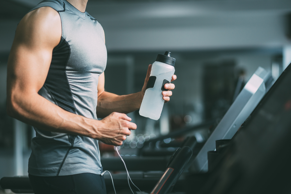 Man on a treadmill holding a bottle of water.
